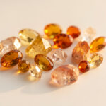 Composition élégante de pierres dorées et d’accents orange sur un fond clair, avec une ambiance chaleureuse et naturelle.